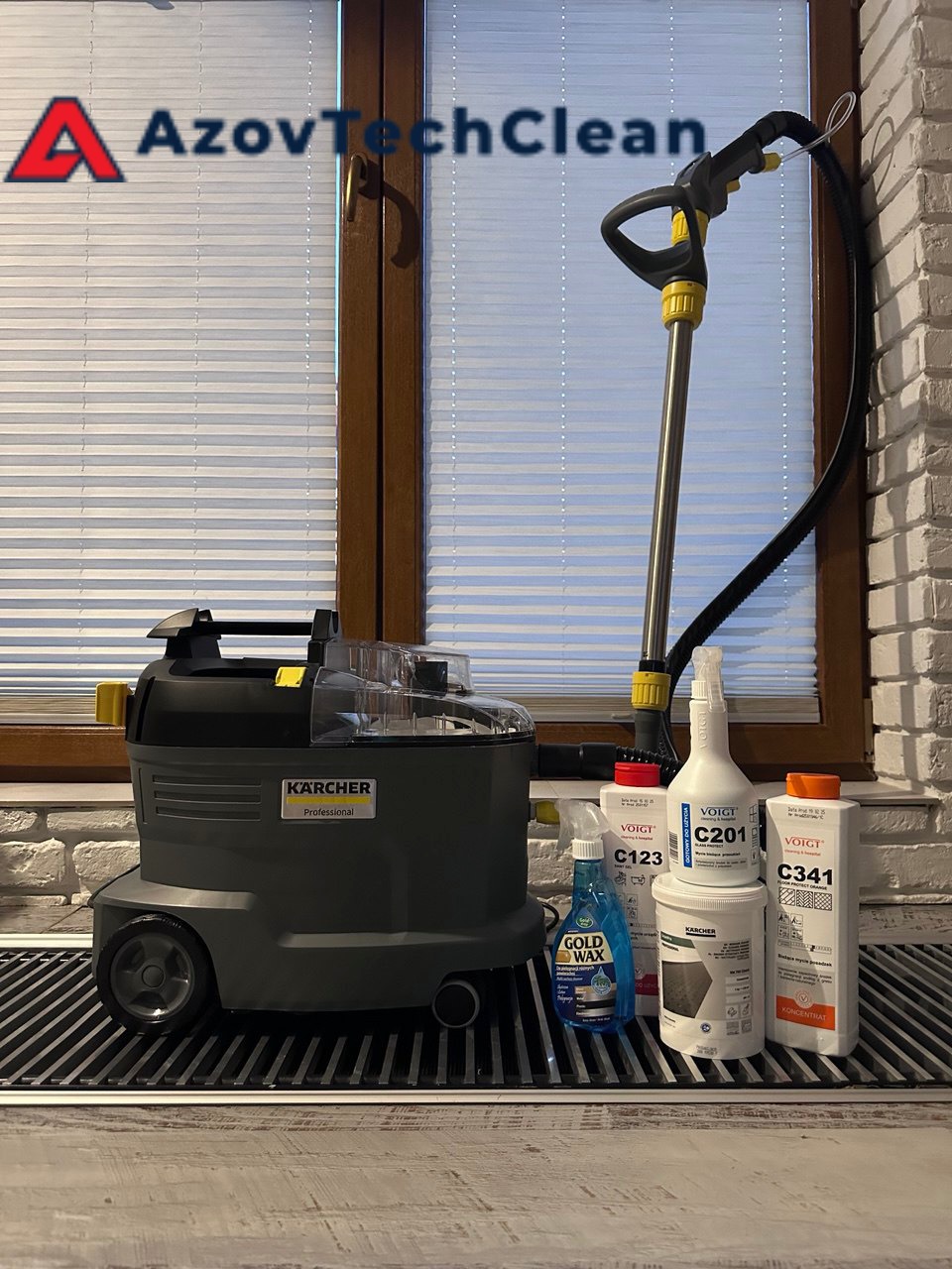 Profesjonalny odkurzacz Karcher, środki czyszczące Voigt C123, C201, C341 oraz Gold Wax na grzejniku, na tle okna z żaluzjami i ceglanej ściany.