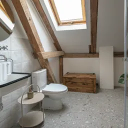 Stylowa łazienka na poddaszu z drewnianymi belkami, białą ceramiką i szarą mozaiką. Uwagę przykuwa retro umywalka i skrzynia z surowego drewna.