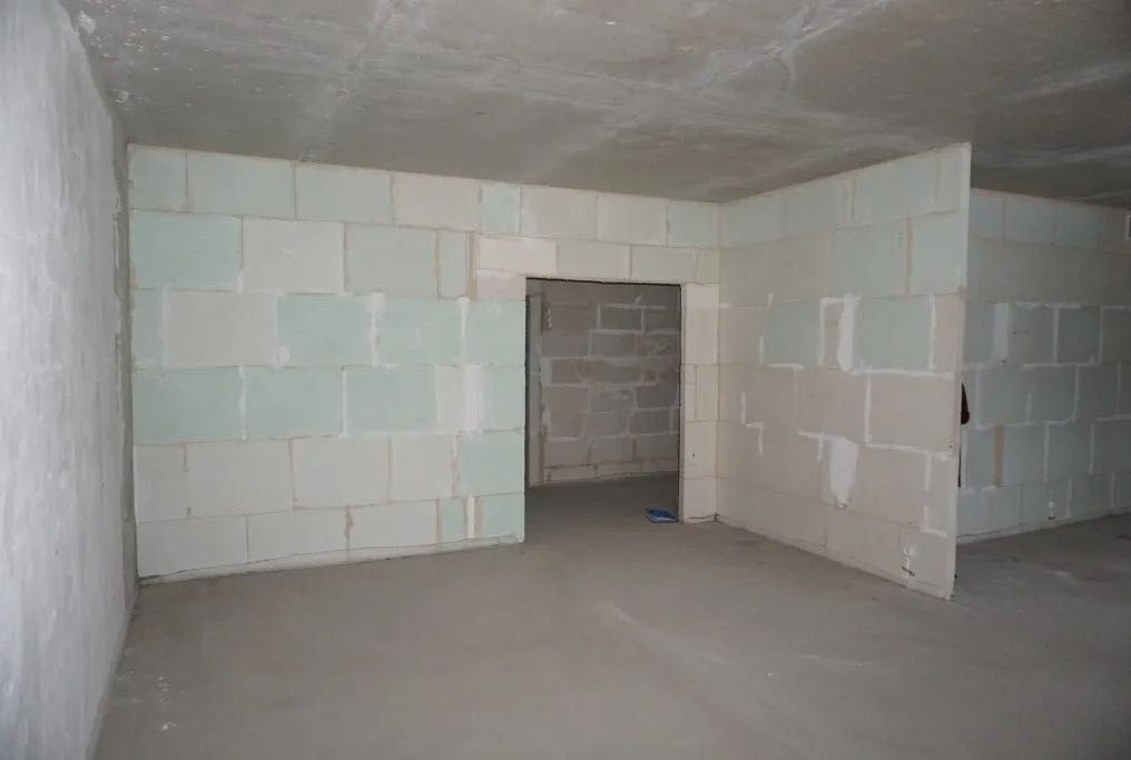Wnętrze w stanie surowym otwartym: ściany z betonu komórkowego, widoczne ślady zaprawy. Sufit betonowy, podłoga wylewka. Otwór drzwiowy w ścianie działowej.
