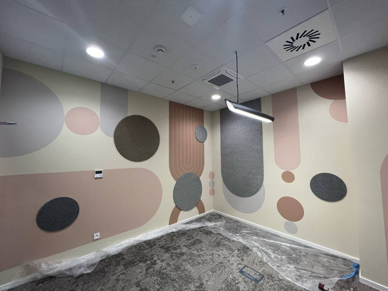 Pokój po dekoracyjnym malowaniu ścian w geometryczne wzory z elementami akustycznymi. Podłoga zabezpieczona folią malarską.