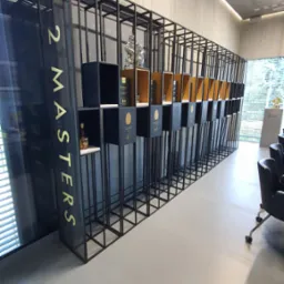 Metalowa, modułowa konstrukcja ekspozycyjna z podświetleniem LED. Czarna rama z półkami prezentującymi produkty. Widok z perspektywy, minimalistyczny design.