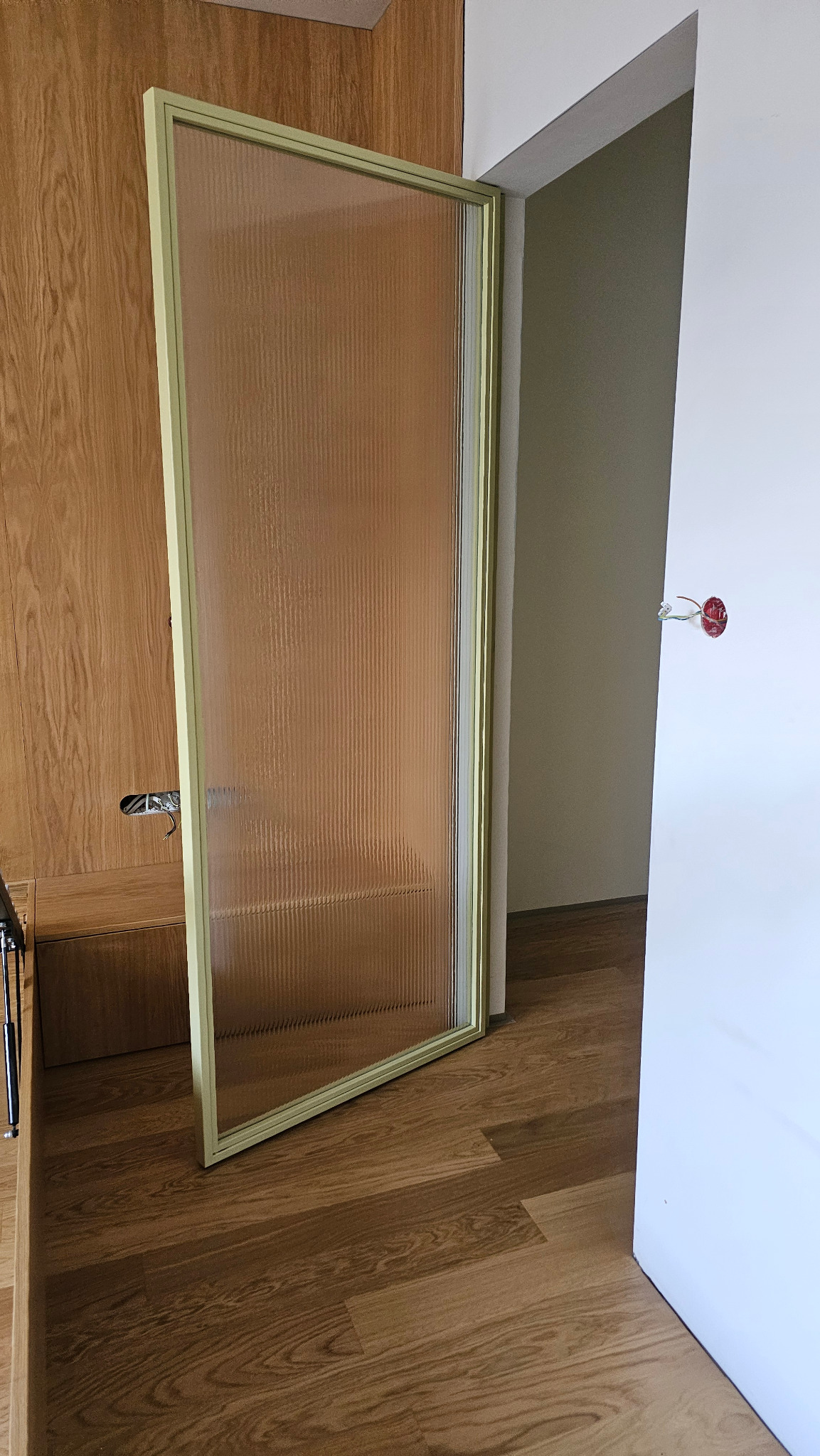 Szklane drzwi do garderoby z profilami stalowymi i szkłem vision sun, zamontowane w drewnianej zabudowie, widok z bliska na fakturę szkła i detale wykończenia.