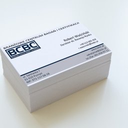 Artiworks Wiesław Małolepszy - Stos wizytówek firmy BCBC z logo i danymi kontaktowymi, ułożonych na białym tle. Wizytówki w odcieniach bieli i szarości, z wyraźnym tekstem i minimalistycznym designem.