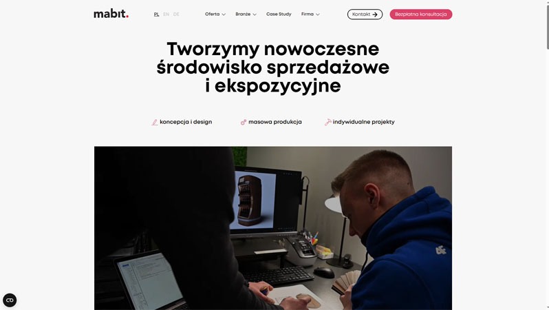 Zespół projektowy pracuje nad wizualizacją 3D ekspozytora na monitorze. Widoczne szkice i laptop. Jasne biuro, nowoczesny design. Koncepcja i design w praktyce.
