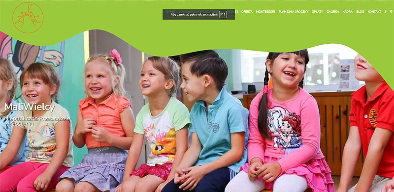 Uśmiechnięte dzieci siedzą obok siebie na tle strony internetowej przedszkola MaliWielcy, z zielonym motywem graficznym u góry. Widoczny fragment menu strony.