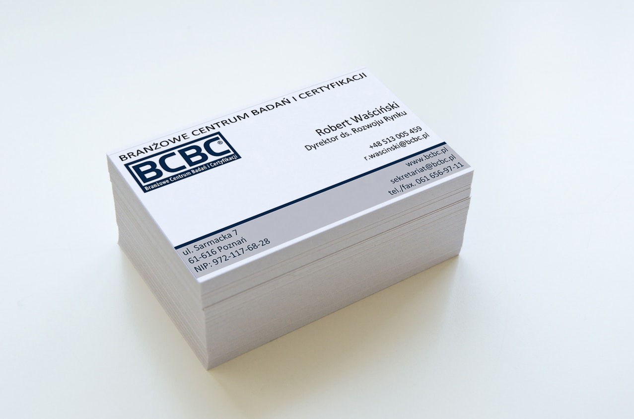 Stos wizytówek firmy BCBC z logo i danymi kontaktowymi, ułożonych na białym tle. Wizytówki w odcieniach bieli i szarości, z wyraźnym tekstem i minimalistycznym designem.