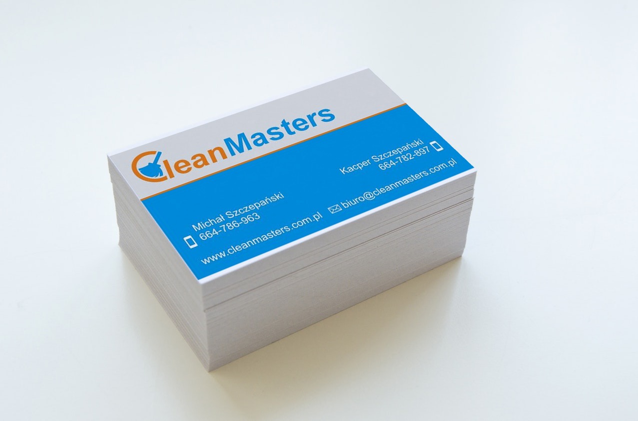 Stos wizytówek firmy CleanMasters z niebieskim tłem i pomarańczowym logo. Widoczne dane kontaktowe: imiona, numery telefonów i adres strony internetowej.