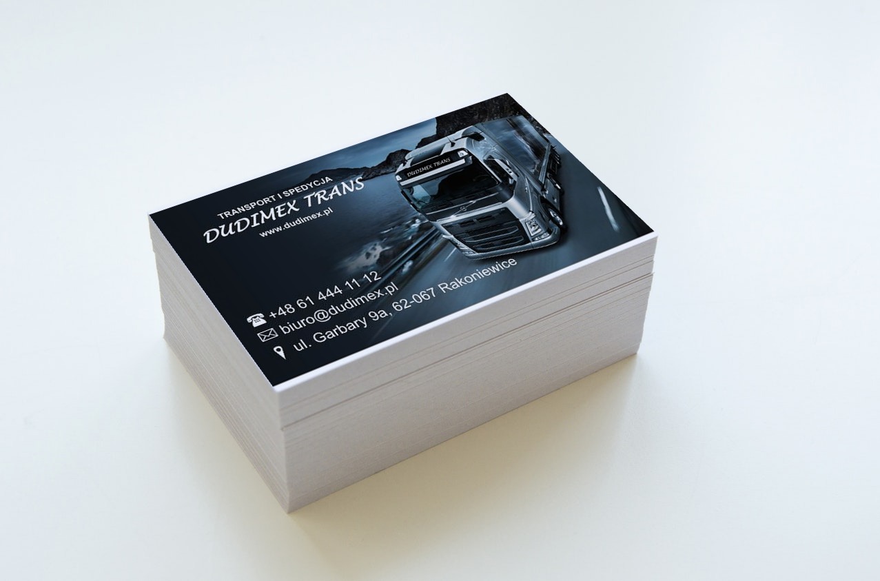 Stos wizytówek firmy transportowej Dudimex Trans z grafiką ciężarówki, na białym tle. Widoczne dane kontaktowe i adres firmy.