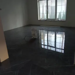 Błyszcząca, ciemna podłoga z płytek imitujących marmur w pustym pokoju. Widoczne duże okno z refleksami światła. Ujęcie z niskiego kąta, podkreślające połysk podłogi.