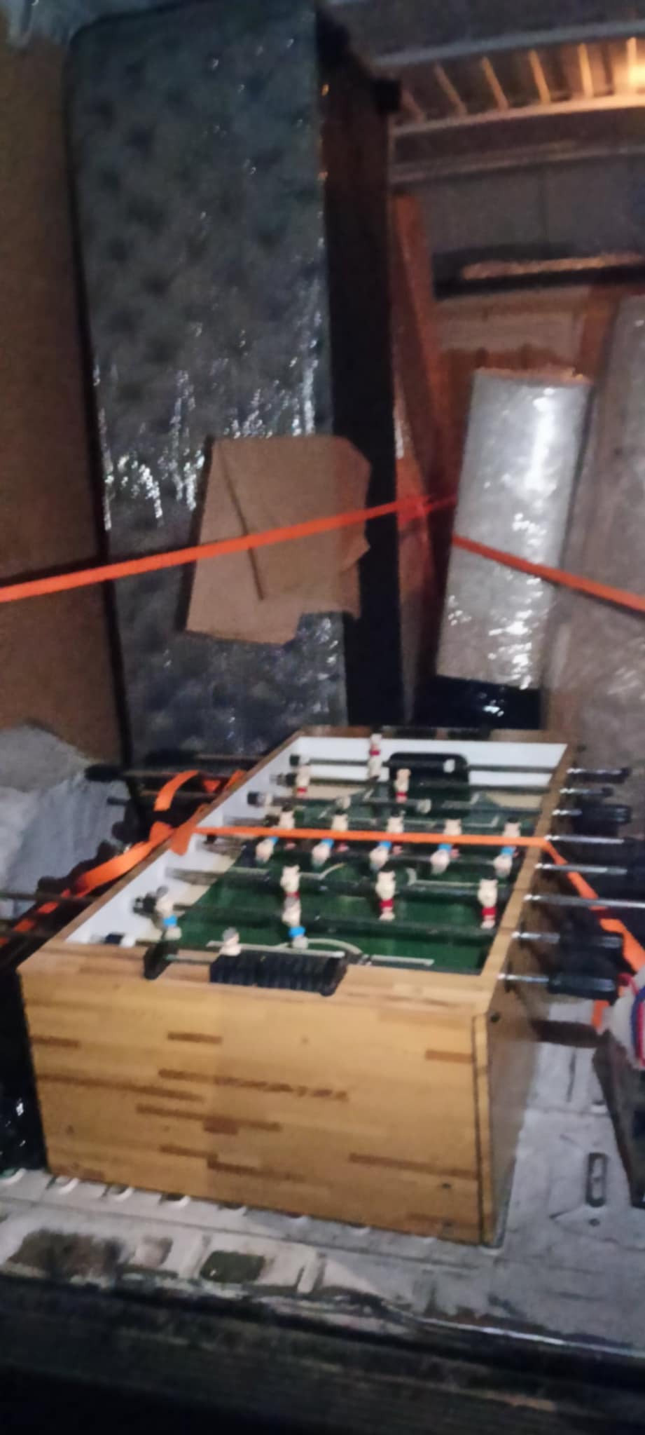 Stół do piłkarzyków zabezpieczony pasami w przestrzeni ładunkowej busa, obok materac w folii i karton. Usługa transportowa, przeprowadzka.