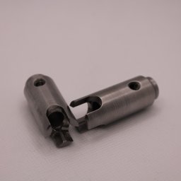 Minitech Adam Palma - Dwie metalowe tuleje z otworem i wycięciem, precyzyjnie obrobione, leżące obok siebie na jasnym tle. Widoczne ślady obróbki skrawaniem.