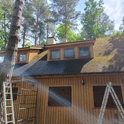 Usługi budowlane Maciej Markiewicz - Dom z drewnianą elewacją przed czyszczeniem dachu z mchu, widoczne rusztowanie i drabiny. Numer domu 99b.