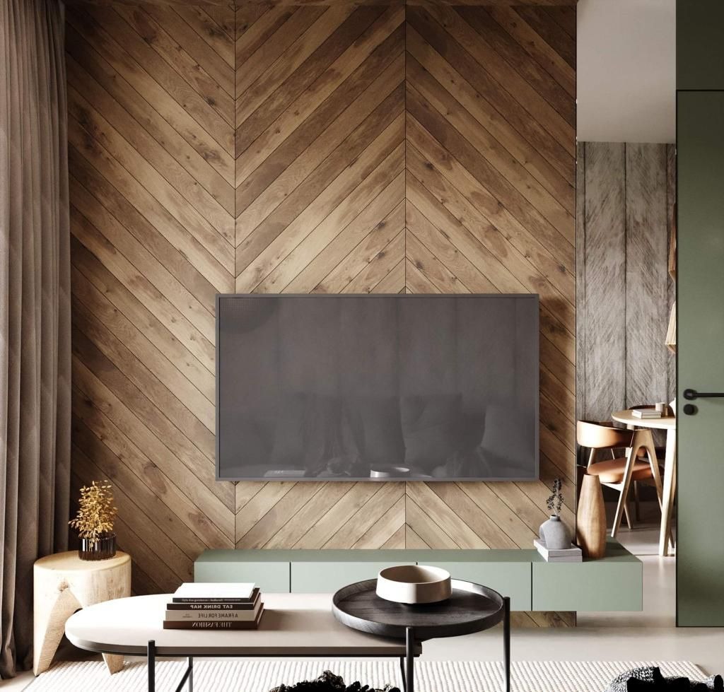 Drewniana ściana z wzorem jodełki za telewizorem. Jasne drewno, minimalistyczny stolik kawowy, zielone akcenty. Nowoczesne wykończenie wnętrza salonu.
