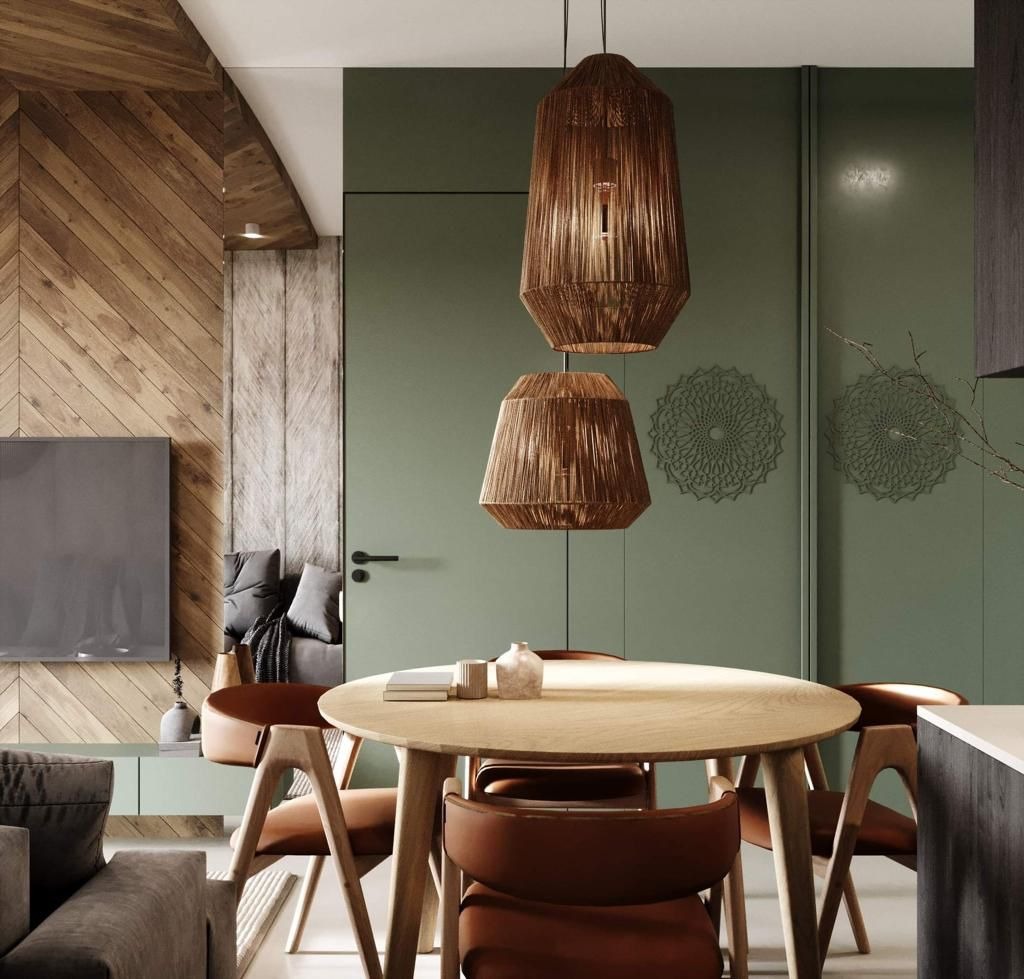 Stylowe wnętrze z drewnianą ścianą w jodełkę, okrągłym stołem z krzesłami i wiszącymi lampami z naturalnego materiału. Dekoracyjne rozety na zielonej ścianie.