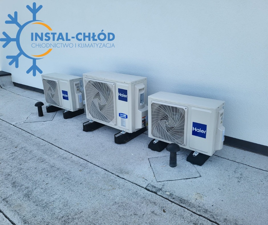 Trzy klimatyzatory Haier na dachu, zamontowane na czarnych podstawach, z widocznymi rurami odprowadzającymi. Logo firmy Instal-Chłód w tle.