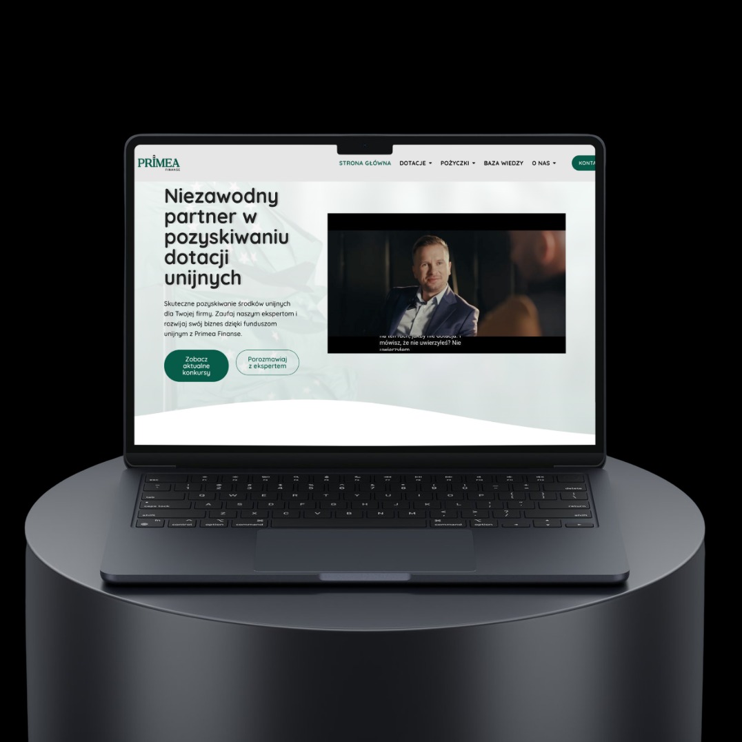 Laptop prezentuje stronę internetową Primea Finanse, oferującą wsparcie w pozyskiwaniu dotacji unijnych. Widoczny fragment strony głównej z nagłówkiem i wideo.
