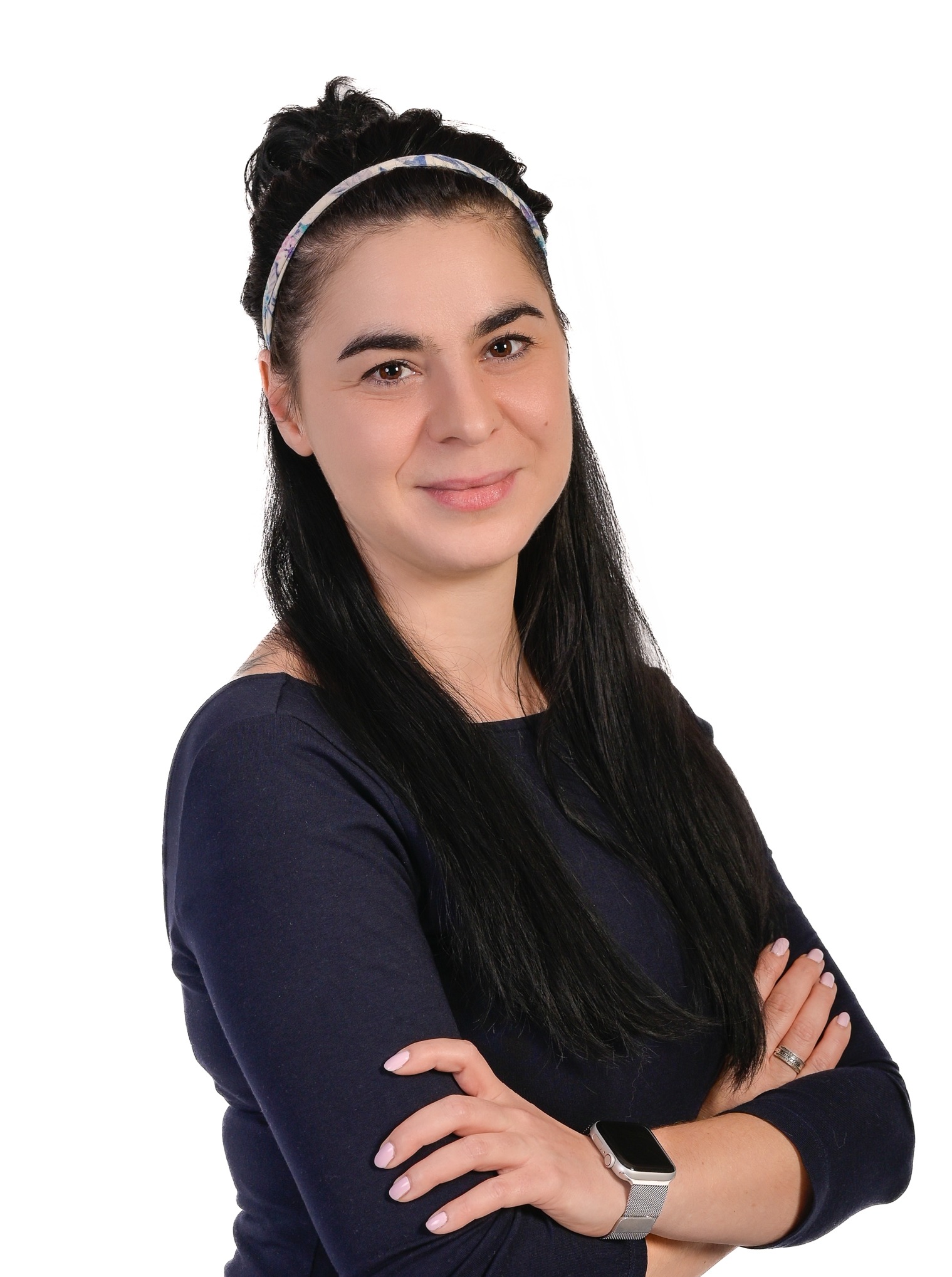 Portret uśmiechniętej kobiety w Warszawie z ciemnymi włosami i opaską, skrzyżowane ręce, smartwatch. Neutralne tło, dobre oświetlenie.