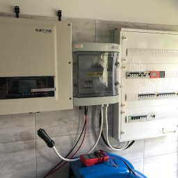 INVICTEL PIKUŁA SPÓŁKA JAWNA - Instalacja elektryczna: falownik Sofar, skrzynka Kenio i rozdzielnica na ścianie z płytkami. Widoczny multimetr i przewody.