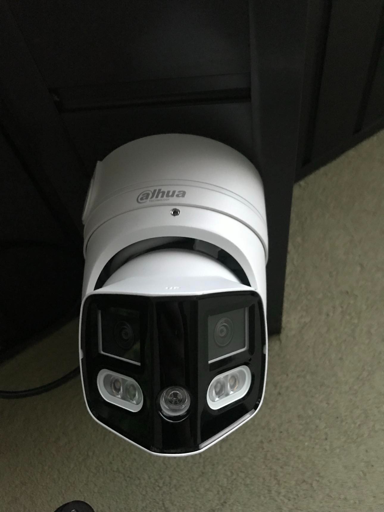 Kamera Dahua IP w obudowie biało-czarnej, zamontowana pod sufitem, skierowana obiektywem w dół. Widoczne diody doświetlające i logo producenta.