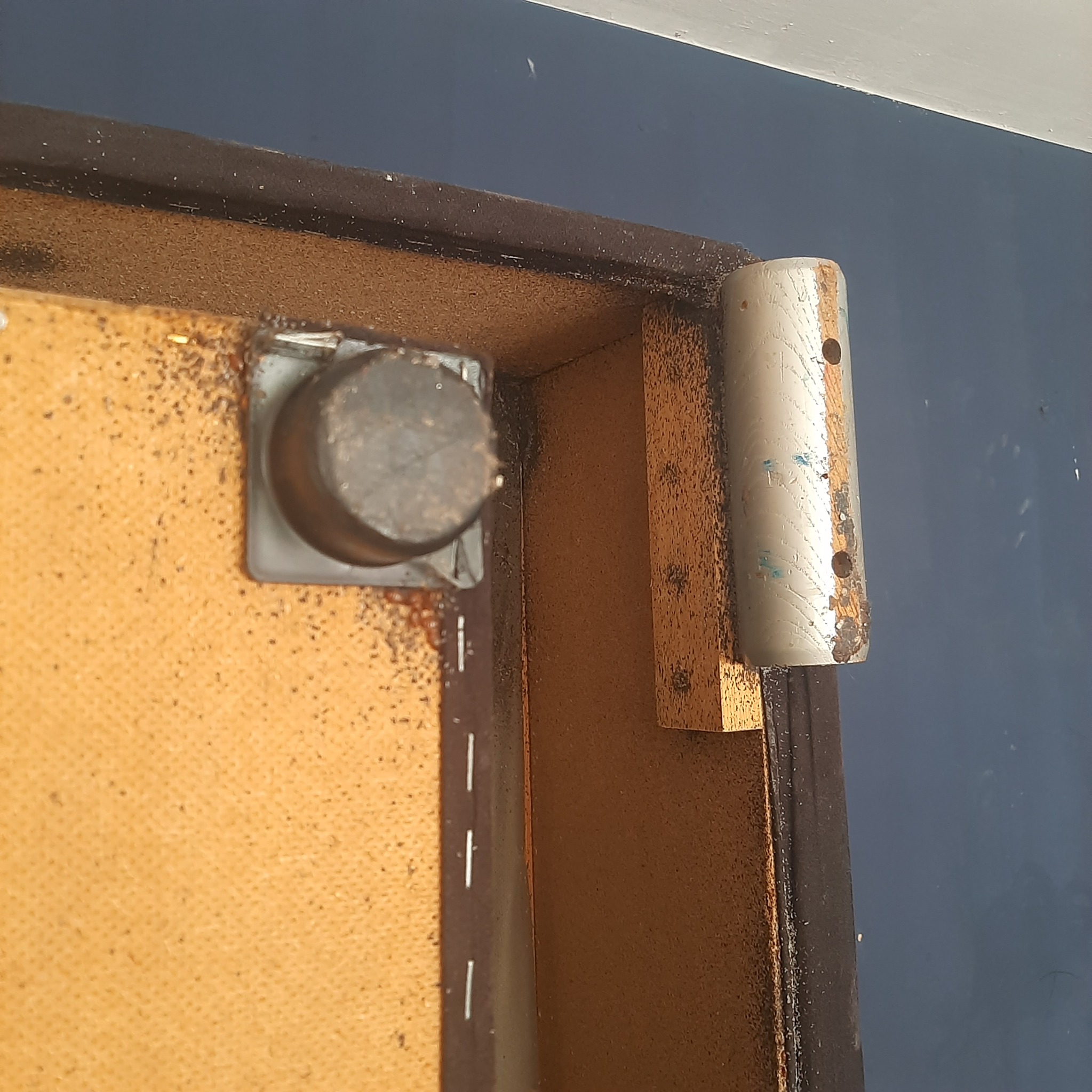 Spód starego mebla z widocznymi śladami obecności owadów, prawdopodobnie po zabiegu dezynsekcji. Widoczne pozostałości insektów. Bliskie ujęcie.