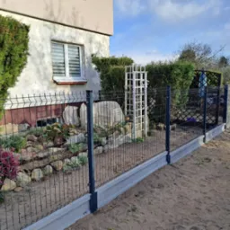 Zamontowane ogrodzenie panelowe z podmurówką przy domu z ogrodem skalnym. Elementy ozdobne w ogrodzeniu.