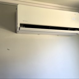 MTech Instalacje S.C. - Biała klimatyzacja Rotenso Versu Series zamontowana na ścianie. Widoczny wyświetlacz z temperaturą 21 stopni. Minimalistyczny design urządzenia.