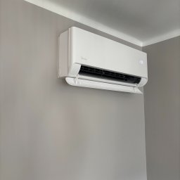 MTech Instalacje S.C. - Biały klimatyzator Midea zamontowany na szarej ścianie w rogu pokoju, widoczny wyświetlacz z temperaturą 17 stopni Celsjusza.