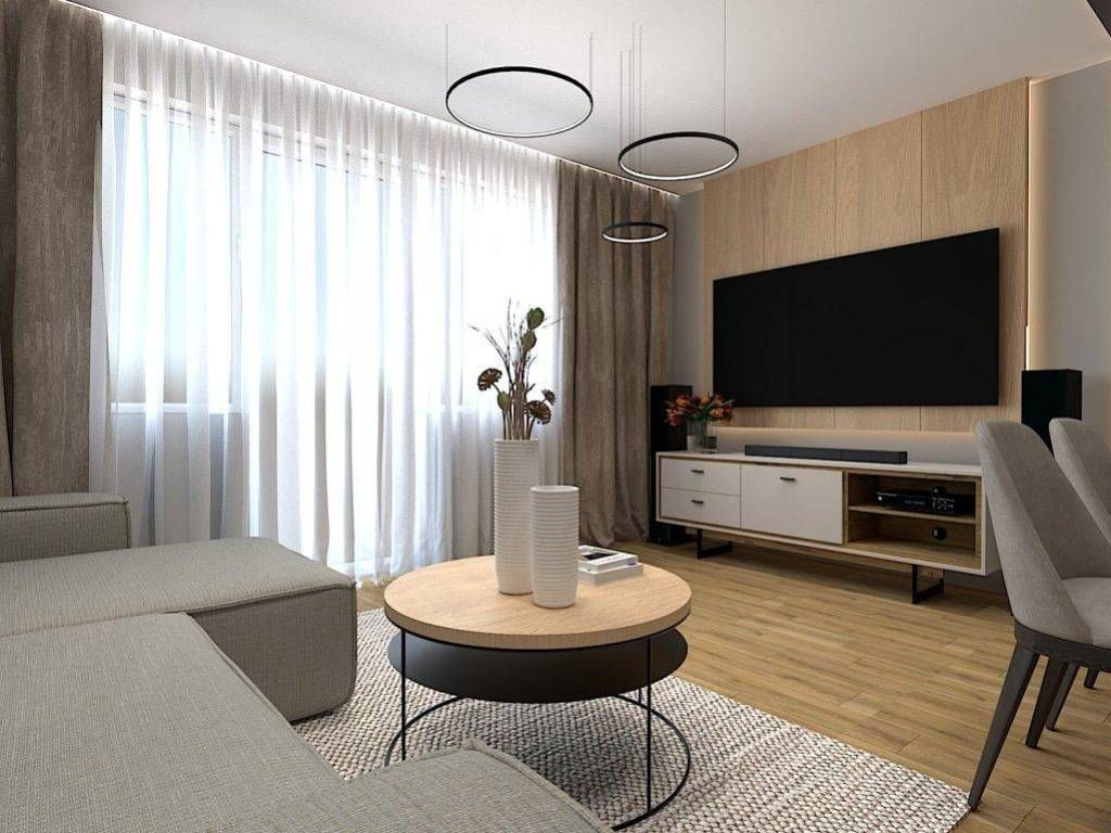 Jasne wnętrze salonu z drewnianą ścianą TV, okrągłym stolikiem kawowym i zasłonami w odcieniach beżu. Minimalistyczne lampy wiszące i dywan w geometryczny wzór.