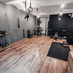 ADRIANA CHRIST REAL FIT - Jasne, przestronne studio treningowe z drewnianą podłogą, wyposażone w sprzęt do ćwiczeń, w tym liny, drabinki i ciężary. Lustrzana ściana.