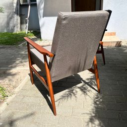 ZURFAM Wojciech Żurawiński - Dwa fotele z drewnianą ramą i szarym obiciem, ustawione na brukowanym patio w słoneczny dzień. Widok z tyłu, z cieniem drzew na ziemi.