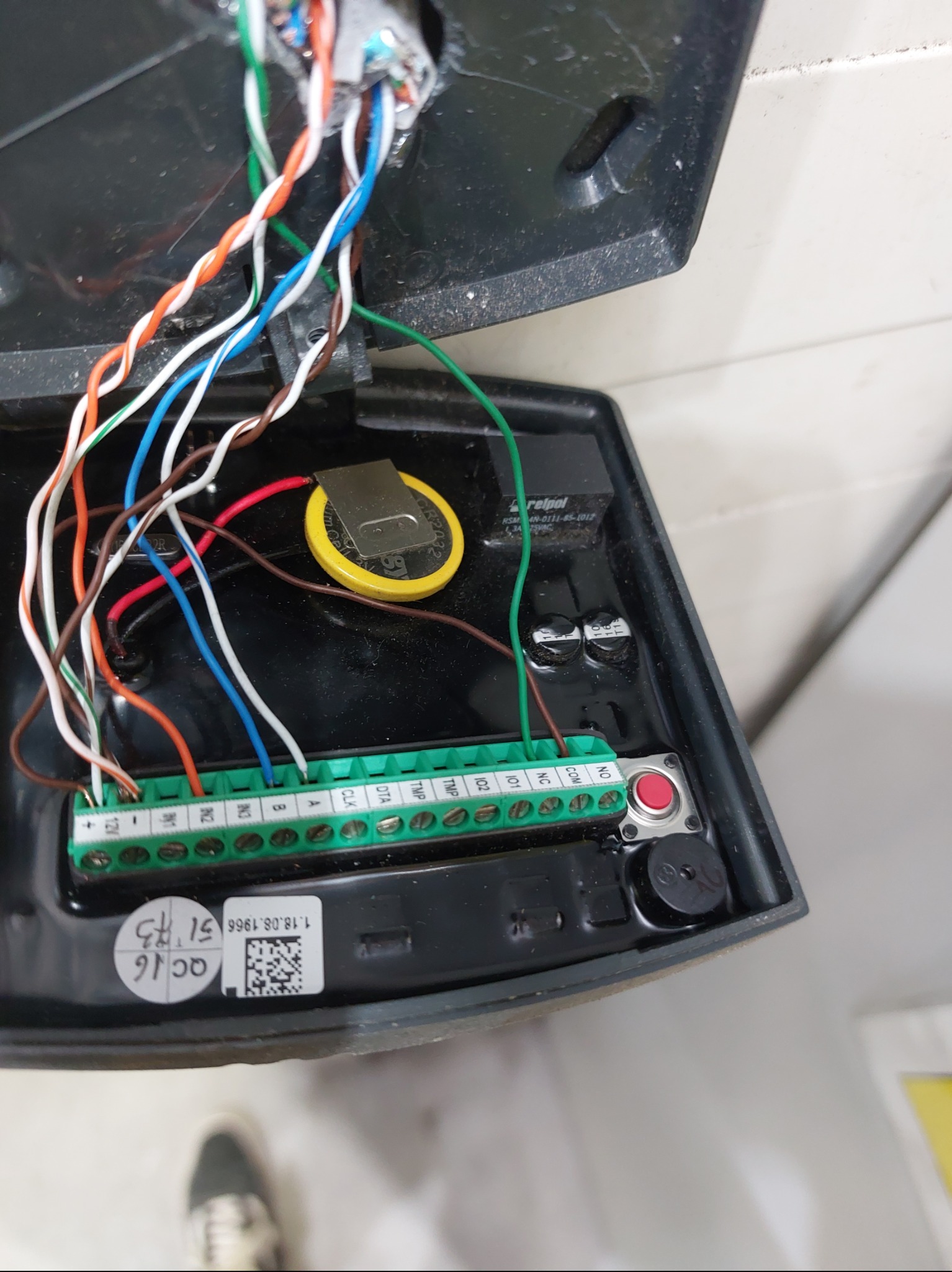 Otwarta obudowa automatu z widocznymi przewodami, zieloną listwą zaciskową, baterią i elementami elektroniki. Widoczne oznaczenia na obudowie.