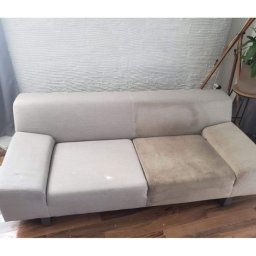 Upaprane - Beżowa sofa: połowa wyczyszczona, druga zabrudzona. Widoczna różnica po praniu tapicerki. W tle ściana z fakturą i roślina doniczkowa.