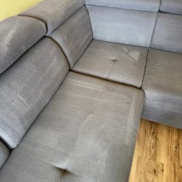 Upaprane - Szary narożnik po praniu: odświeżona tapicerka, brak plam i zapachów. Widoczne ślady wilgoci po czyszczeniu. Parkiet w tle. Ujęcie z bliska, prezentujące efekt usługi.