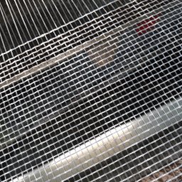 PPH SÓLMET Marek Maciocha - Siatka filtracyjna o drobnych oczkach, ukośnie ułożona, z widocznymi cienkimi, metalowymi prętami w tle. Element studni głębinowej.