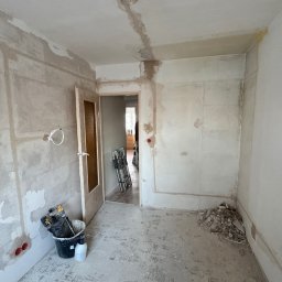 EL-Ryś - Remont pokoju: ściany w szpachli, widoczne kable elektryczne, narzędzia w wiadrze. Przygotowanie do malowania, widoczne ślady po instalacjach.