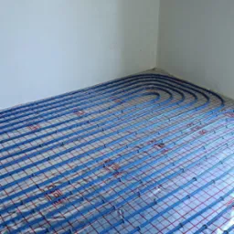 Instalacja ogrzewania podłogowego z rurami w kolorze niebieskim na folii aluminiowej, widok z góry w pomieszczeniu w Dobczycach.