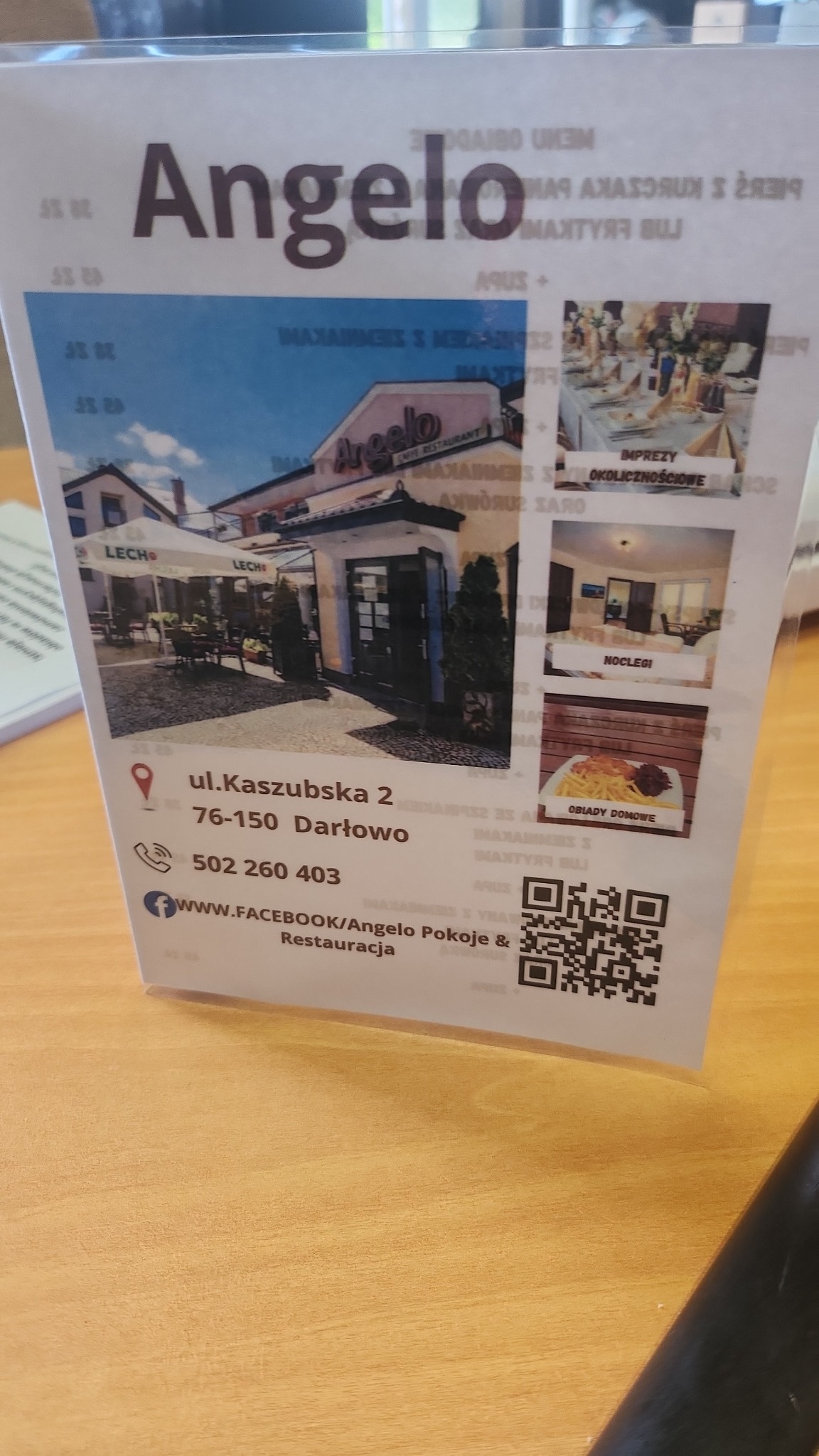 Stojak reklamowy restauracji Angelo z Darłowa, prezentujący zdjęcia lokalu, ofertę noclegów, imprez okolicznościowych, adres, telefon i kod QR do Facebooka.