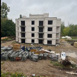 OLEH STOLIAR DOM BUD - Surowy stan budynku wielorodzinnego z betonu komórkowego, z widocznymi rusztowaniami i materiałami budowlanymi na placu budowy, pochmurny dzień.