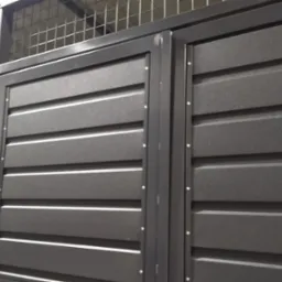 Szara metalowa brama z poziomymi panelami i kratką u góry, mocowana na nity.