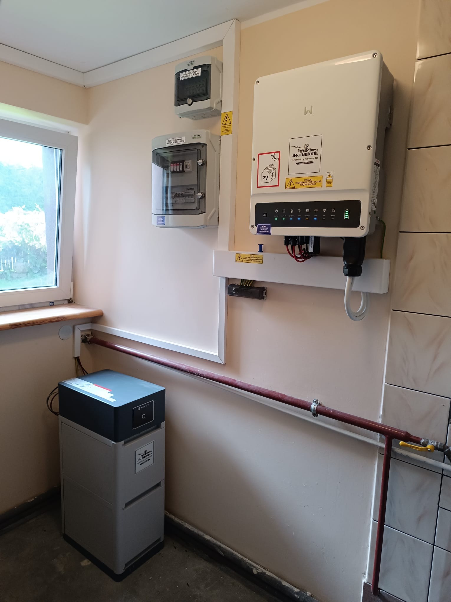 Kompletna instalacja fotowoltaiczna z magazynem energii wewnątrz budynku w Radosiewie. Widoczny inwerter, rozdzielnica i bateria.