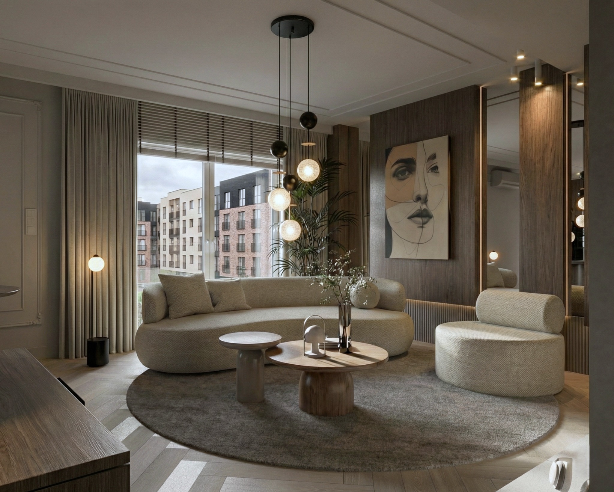 Neutralna kolorystyka salonu z okrągłym dywanem, sofą o obłych kształtach, stolikami kawowymi i lampą wiszącą. Na ścianie obraz z motywem twarzy.