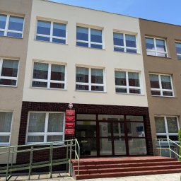 Halbud Taras Halats - Budynek szkoły po renowacji elewacji, z widocznymi dwoma odcieniami beżu i brązu. Wejście z rampą dla niepełnosprawnych i tabliczkami informacyjnymi.