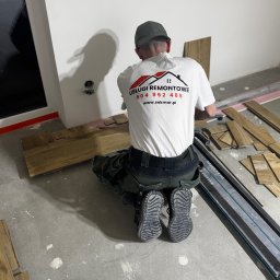 SEK-MAR SP.ZO.O. - Pracownik w firmowej koszulce układa panele podłogowe w nowym pomieszczeniu. Widoczny profesjonalny sprzęt do cięcia paneli i przygotowane deski.