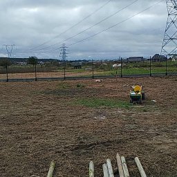 Paweł Tyman spawalnia - Montaż ogrodzenia panelowego z betonową podmurówką na posesji, widok na teren przygotowany pod trawnik, w tle słupy wysokiego napięcia i zabudowa wiejska.