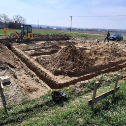 MARCIN KRÓL USŁUGI MINIKOPARKĄ MAJS-KOP - Wykop pod fundamenty z użyciem minikoparki JCB, widoczne wytyczone granice, urobiona ziemia i osoba nadzorująca prace. Prace ziemne w terenie otwartym.
