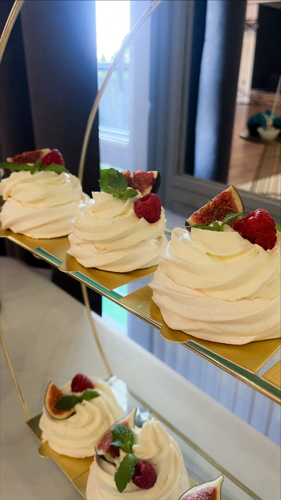 Eleganckie mini bezy Pavlova z figami, malinami i miętą, ułożone na złotej paterze. Delikatne desery na przyjęcie, cukiernicza precyzja, jasne wnętrze.