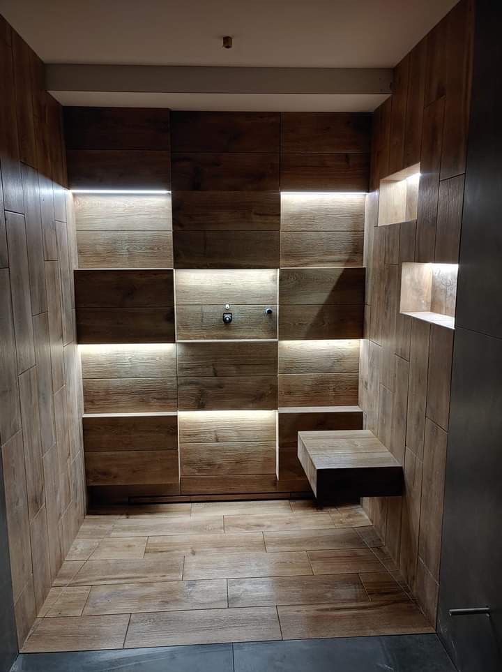 Nowoczesna kabina prysznicowa z drewnopodobnymi płytkami, podświetleniem LED i półką wnękową. Minimalistyczny design, ciepłe oświetlenie, teksturalne wykończenie.