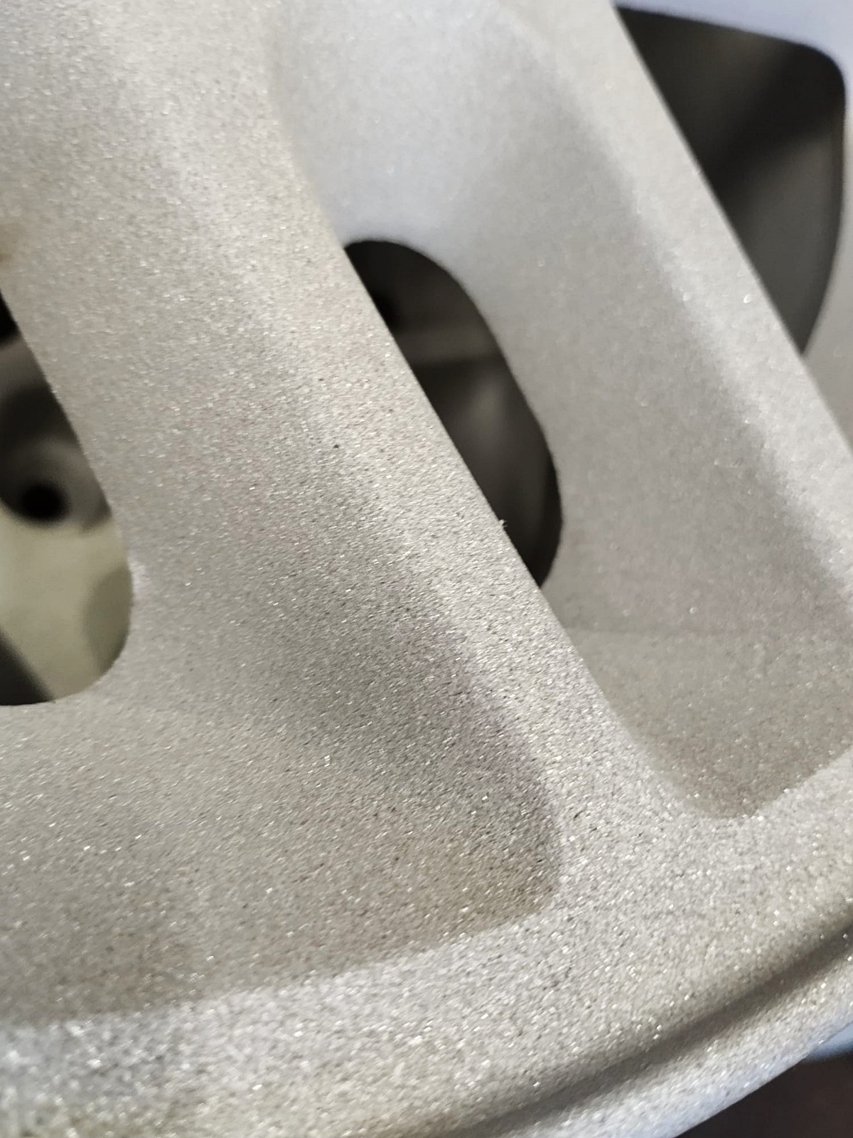 Szczegółowe ujęcie felgi aluminiowej po piaskowaniu, ukazujące jednolitą, matową powierzchnię i otwory. Widoczna delikatna tekstura po obróbce.