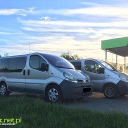 Szymon Walczak - Dwa srebrne busy Renault Trafic zaparkowane przed myjnią samochodową w słoneczny dzień, widoczne logo firmy Turek.net.pl w lewym dolnym rogu.