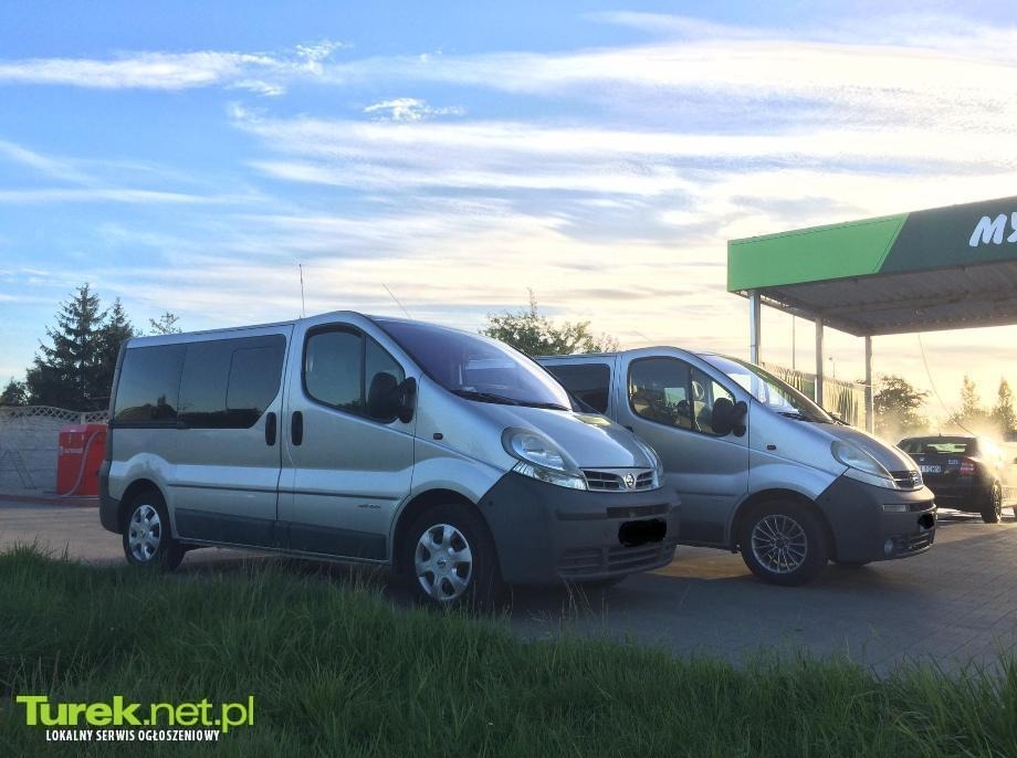 Dwa srebrne busy Renault Trafic zaparkowane przed myjnią samochodową w słoneczny dzień, widoczne logo firmy Turek.net.pl w lewym dolnym rogu.